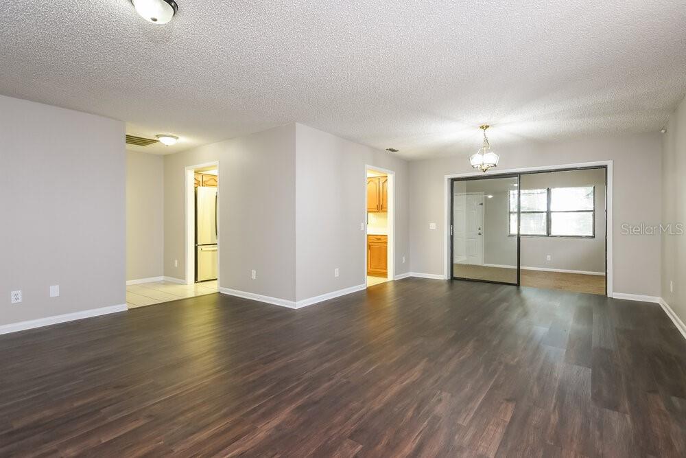 An interior view of a living area with dark wood-look flooring and sliding glass doors — 104 LAKE DAISY TERRACE, WINTER HAVEN, FL