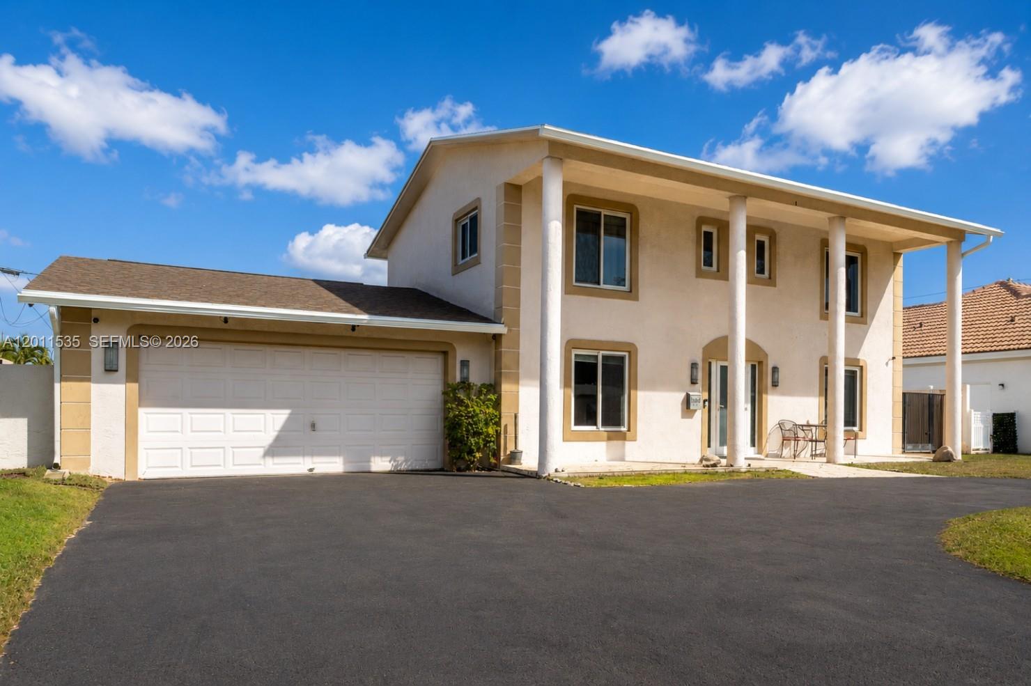 A two-story house with a beige stucco exterior, white columns, and an attached garage — 1660 NE 25th Ave, Pompano Beach FL 33062, POMPANO BEACH, FL