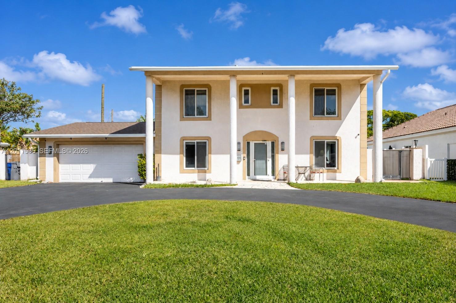 A two-story house with a circular driveway, white columns, and a garage under a blue sky — 1660 NE 25th Ave, Pompano Beach FL 33062, POMPANO BEACH, FL
