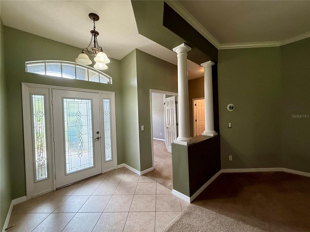 An entryway features tile flooring, sage green walls, a decorative front door, and white columns — 5126 MAJESTIC WOODS PL, SANFORD, FL
