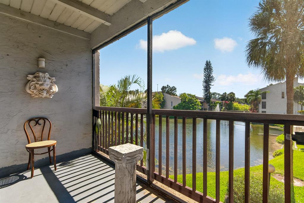 A screened-in balcony overlooks a pond with a fountain and surrounding apartment buildings — 8602 CHAMPLAIN COURT UNIT 93, TAMPA, FL