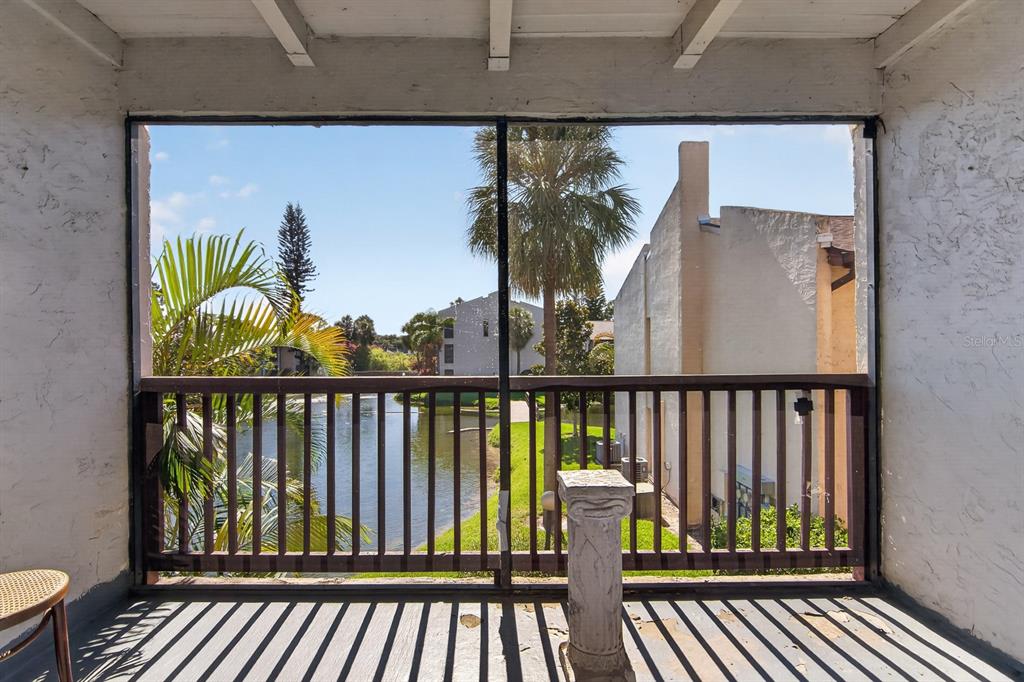 A screened-in balcony overlooks a pond and neighboring apartment buildings on a sunny day — 8602 CHAMPLAIN COURT UNIT 93, TAMPA, FL