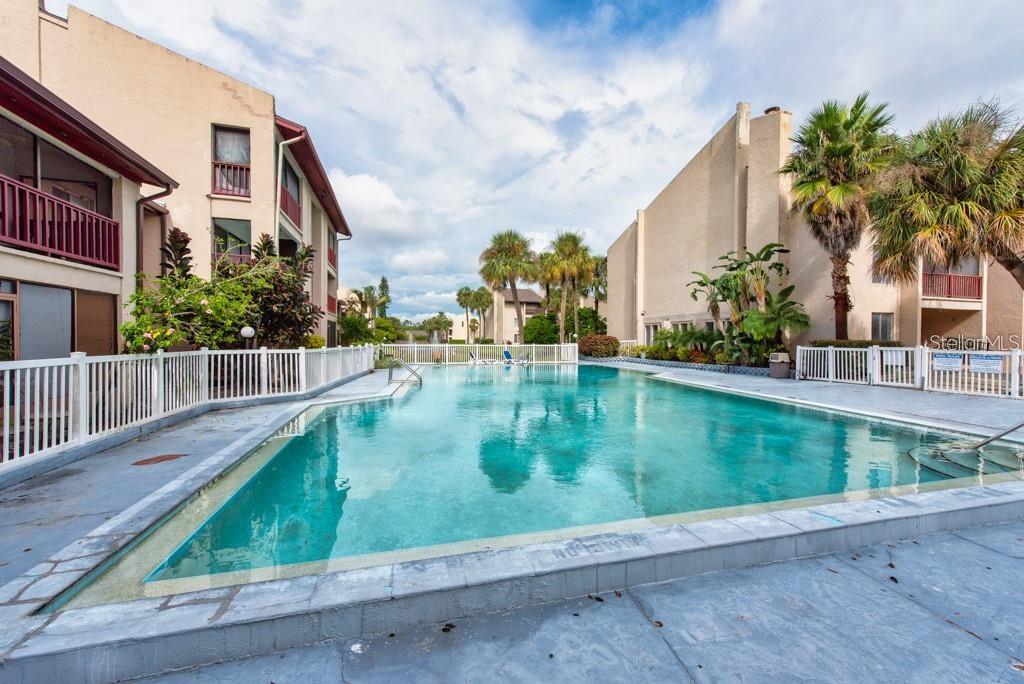 An outdoor swimming pool surrounded by apartment buildings and palm trees — 8602 CHAMPLAIN COURT UNIT 93, TAMPA, FL