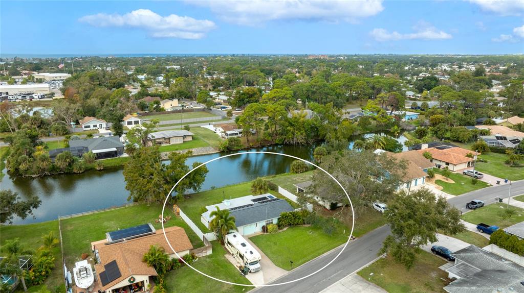 An aerial view shows a single-story house with a parked RV and a waterfront backyard — 2165 LAKEWOOD DRIVE, NOKOMIS, FL