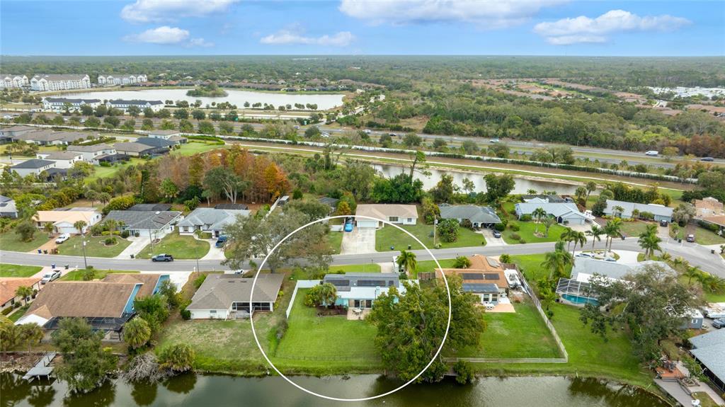 An aerial view shows a residential house with a large backyard bordering a lake — 2165 LAKEWOOD DRIVE, NOKOMIS, FL