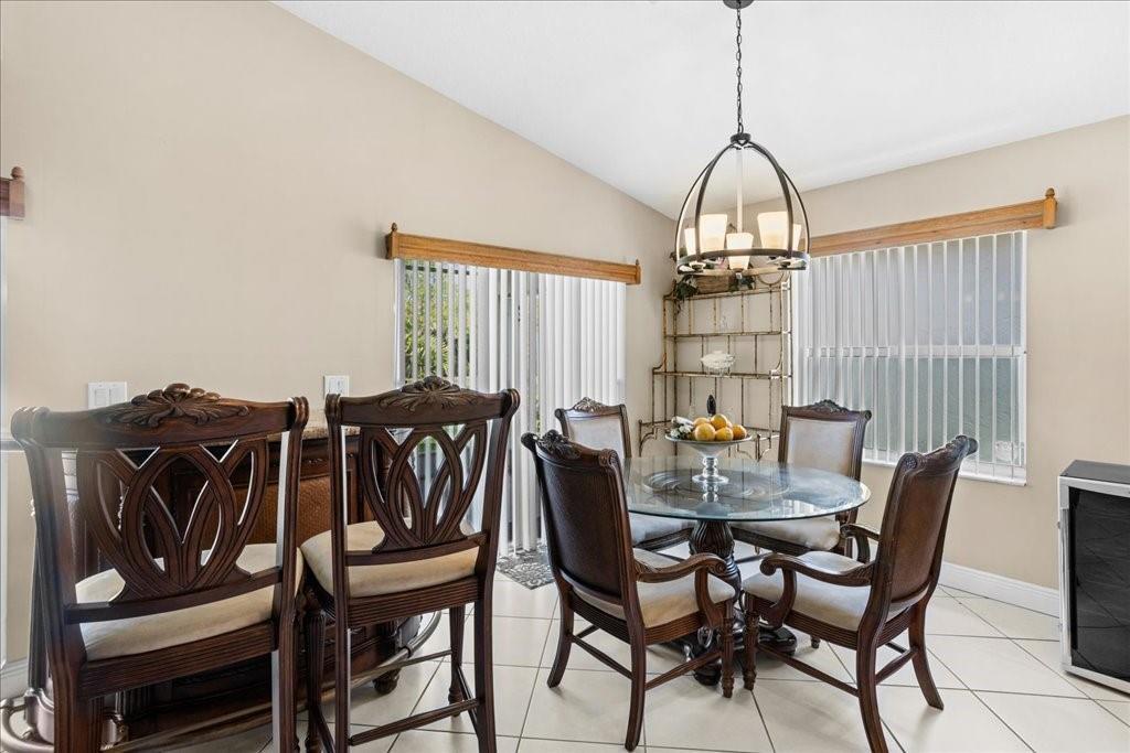 A dining area features a glass-topped table, wooden chairs, and a metal chandelier — 6358 Westchester Club Drive, Boynton Beach FL 33437, BOYNTON BEACH, FL