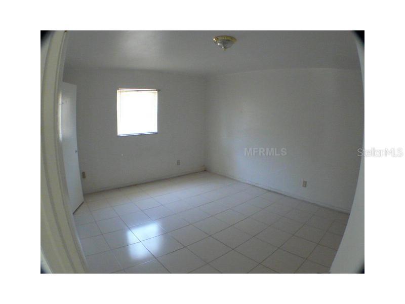 An empty room features white walls, a single window, and light-colored tile flooring — 895 PASADENA AVENUE, LONGWOOD, FL
