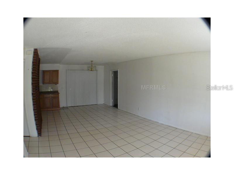 An open-concept living area features white tile flooring, white walls, and a small kitchen corner — 895 PASADENA AVENUE, LONGWOOD, FL
