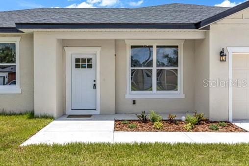The exterior of a house features a white front door, a window, and a walkway — 2524 MAXIMUS COURT, DELTONA, FL