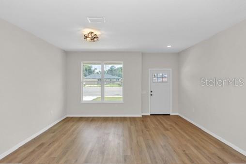 An empty room with light gray walls, wood-look flooring, a window, and a white door — 2524 MAXIMUS COURT, DELTONA, FL
