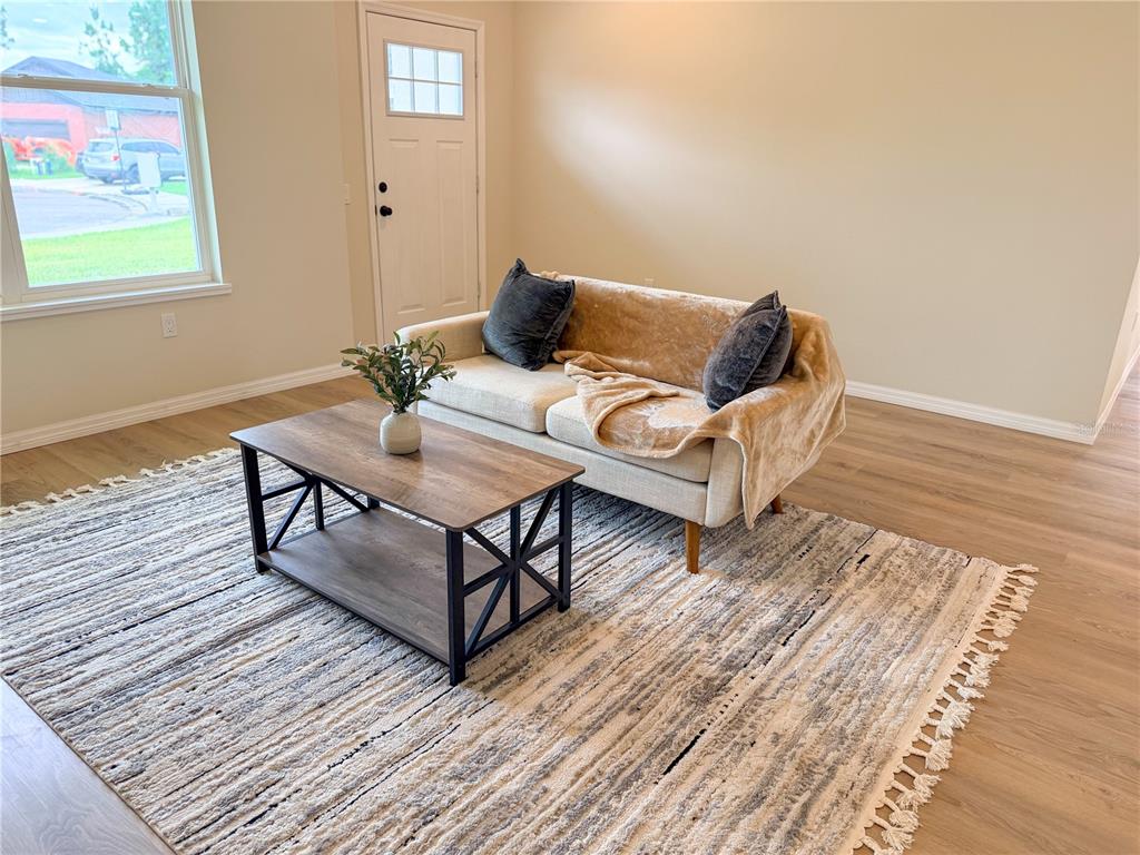 A living room features a beige sofa, a wood coffee table, and a textured rug — 2524 MAXIMUS COURT, DELTONA, FL
