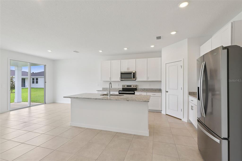 A kitchen with white cabinets, granite countertops, a center island, and stainless steel appliances — 73 WANDERING CREEK WAY, PALM COAST, FL
