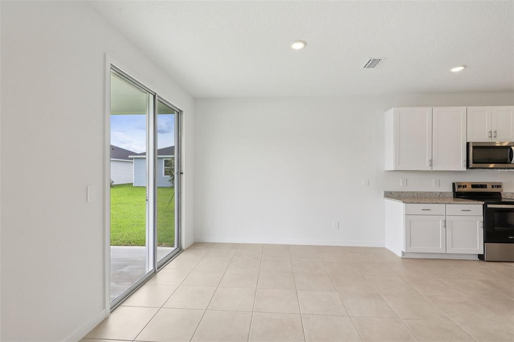 A bright dining area features tile flooring, white walls, and a sliding glass patio door — 73 WANDERING CREEK WAY, PALM COAST, FL