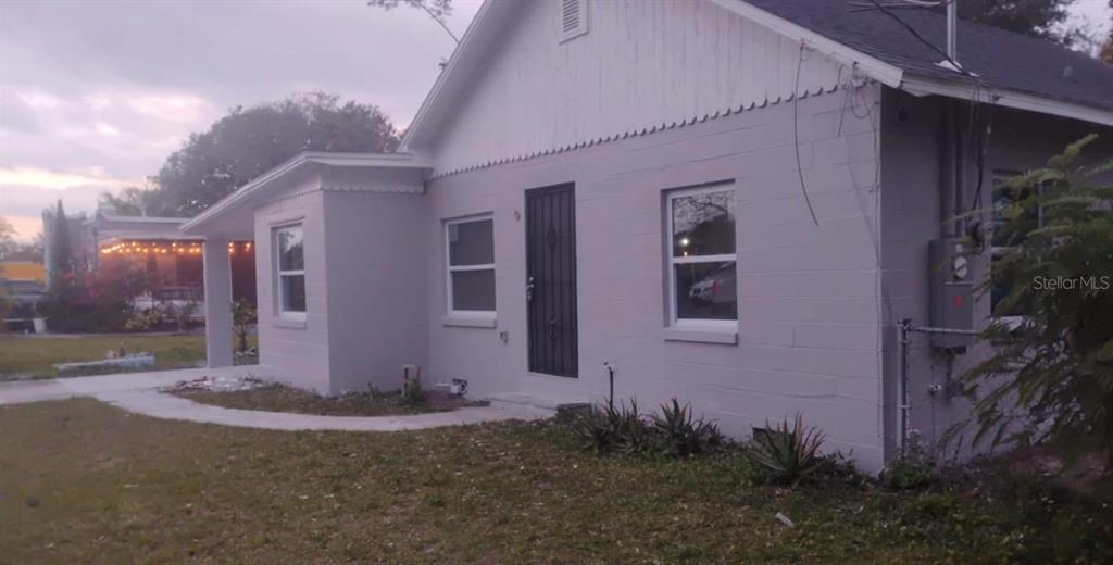 A single-story house with light gray concrete block walls and a dark front door — 110 N GOLDWYN AVENUE, ORLANDO, FL
