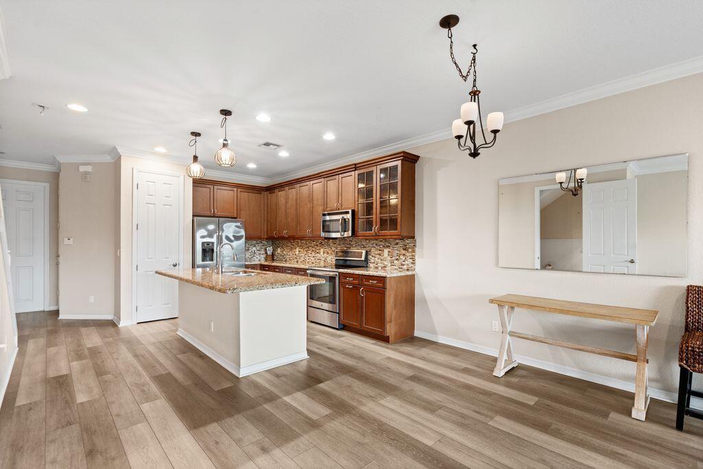 A kitchen with wood cabinets, granite countertops, an island, and wood-look flooring — 626 SW Glen Crest Way, Stuart FL 34997, STUART, FL