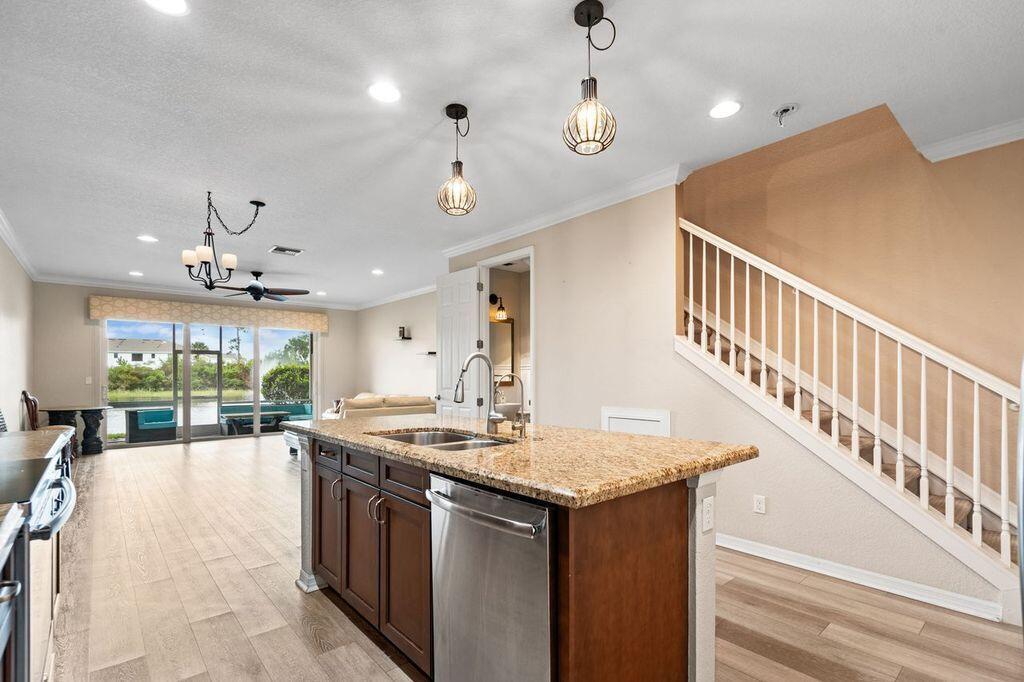 A kitchen with a granite-topped island and stainless steel appliances overlooks a living area — 626 SW Glen Crest Way, Stuart FL 34997, STUART, FL