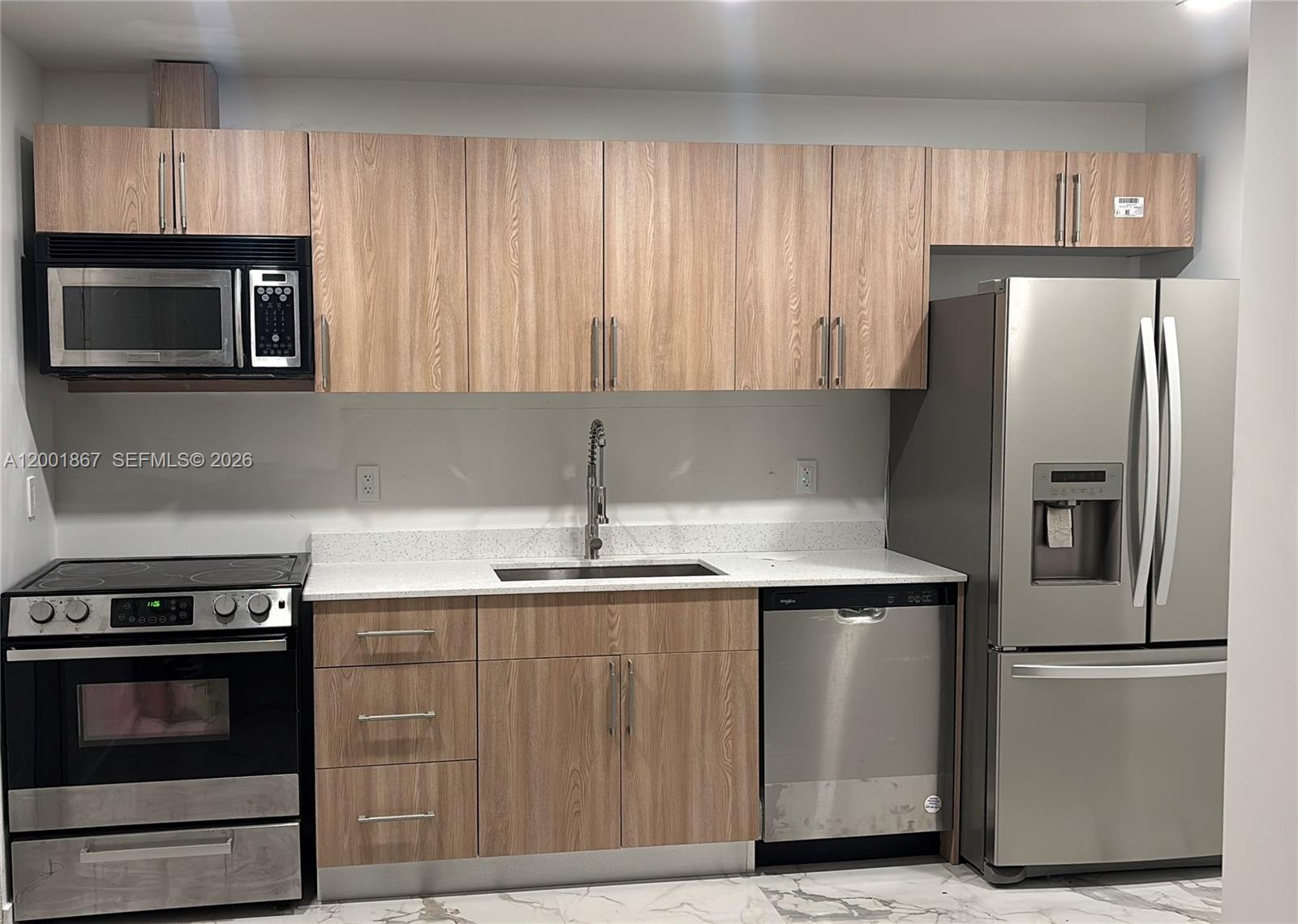 A kitchen features light wood cabinets, stainless steel appliances, and white speckled countertops — 1629 Mayo St, Hollywood FL 33020, HOLLYWOOD, FL
