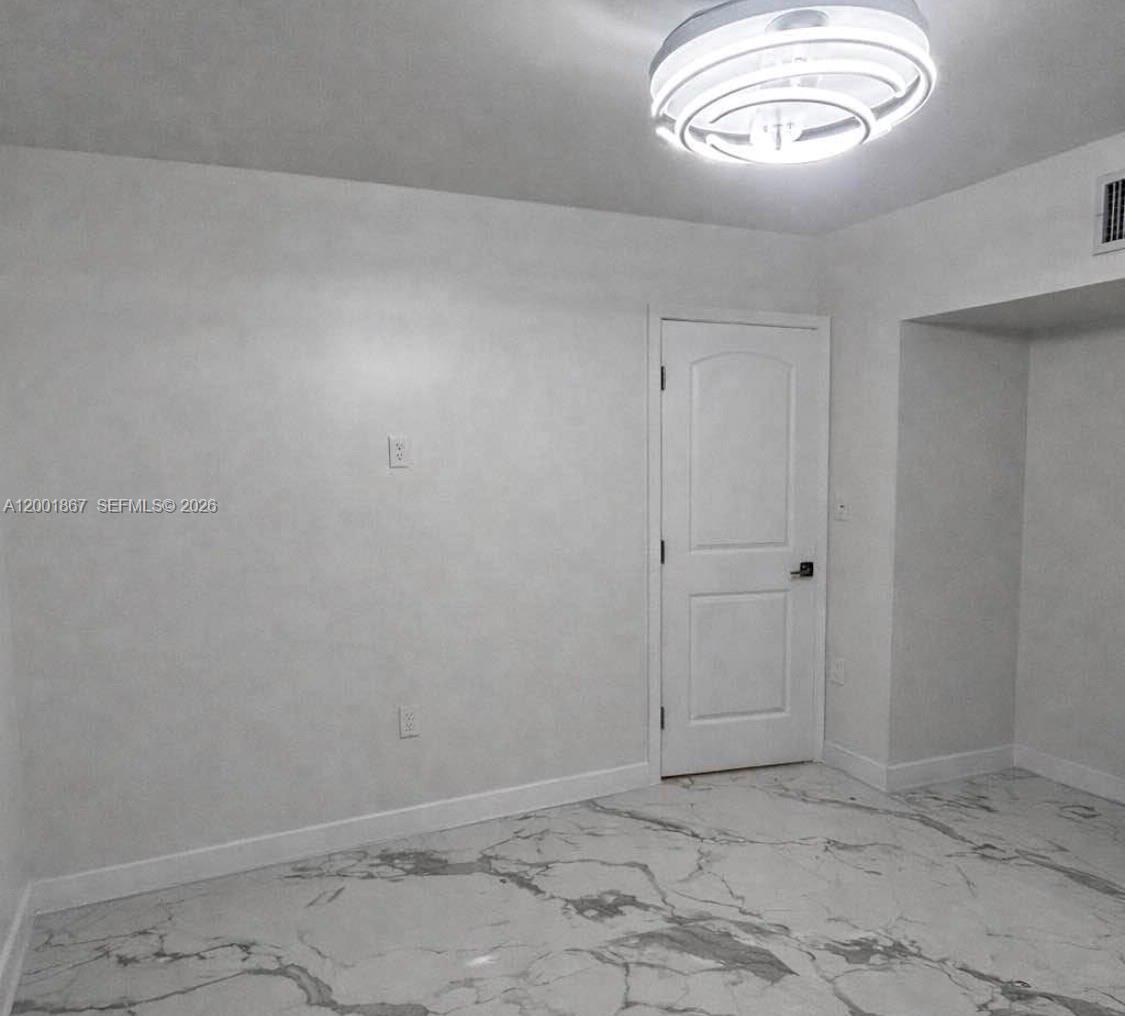A room with white walls, a white door, and white marble-patterned tile flooring — 1629 Mayo St, Hollywood FL 33020, HOLLYWOOD, FL