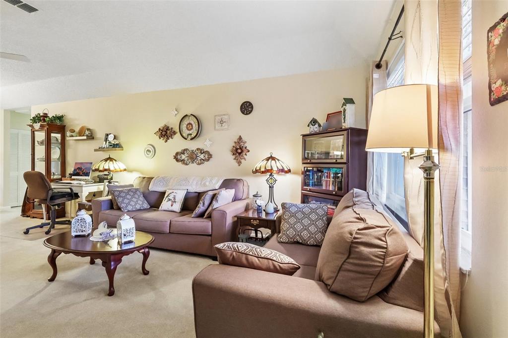 A living room features two brown sofas, a coffee table, and wall-mounted decorative accents — 4890 PLEASANT HOLLOW TRAIL, LAKELAND, FL
