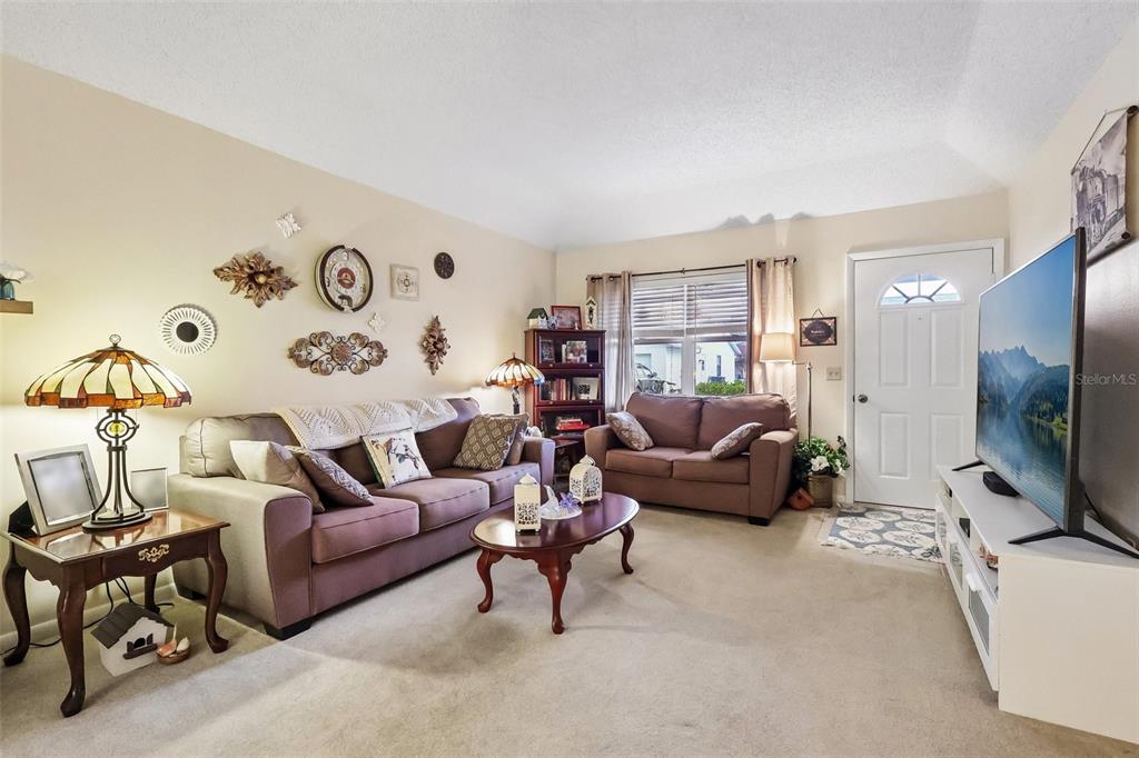 A living room features a brown sofa, a matching loveseat, and a large television — 4890 PLEASANT HOLLOW TRAIL, LAKELAND, FL