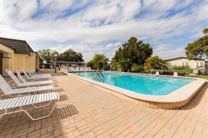 An outdoor swimming pool with lounge chairs on a paved deck under a cloudy sky — 6418 KILOHEE COURT, NORTH PORT, FL