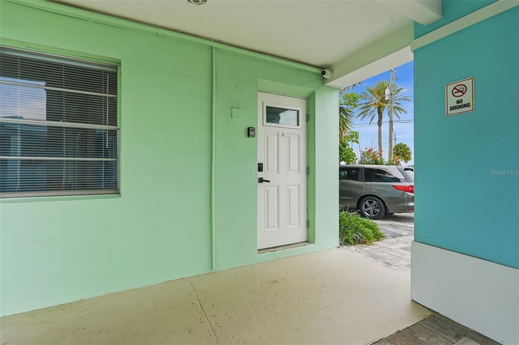 A white door with a keypad lock sits under a covered entryway with pastel walls — 17880 GULF BOULEVARD UNIT 2, ST PETERSBURG, FL