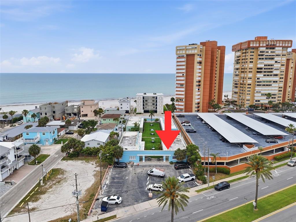 An aerial view shows a light blue building with a courtyard and adjacent parking lot — 17880 GULF BOULEVARD UNIT 2, ST PETERSBURG, FL