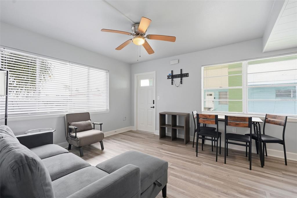 A living and dining area features light wood flooring, a ceiling fan, and large windows — 17880 GULF BOULEVARD UNIT 2, ST PETERSBURG, FL
