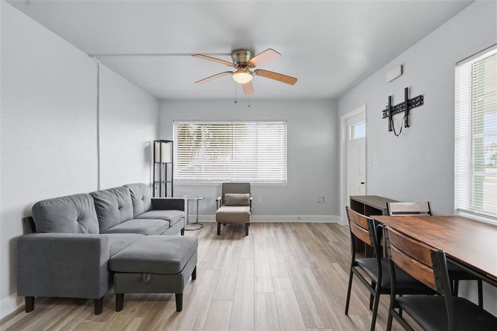 A living room features a gray sectional sofa, a dining table, and light wood flooring — 17880 GULF BOULEVARD UNIT 2, ST PETERSBURG, FL