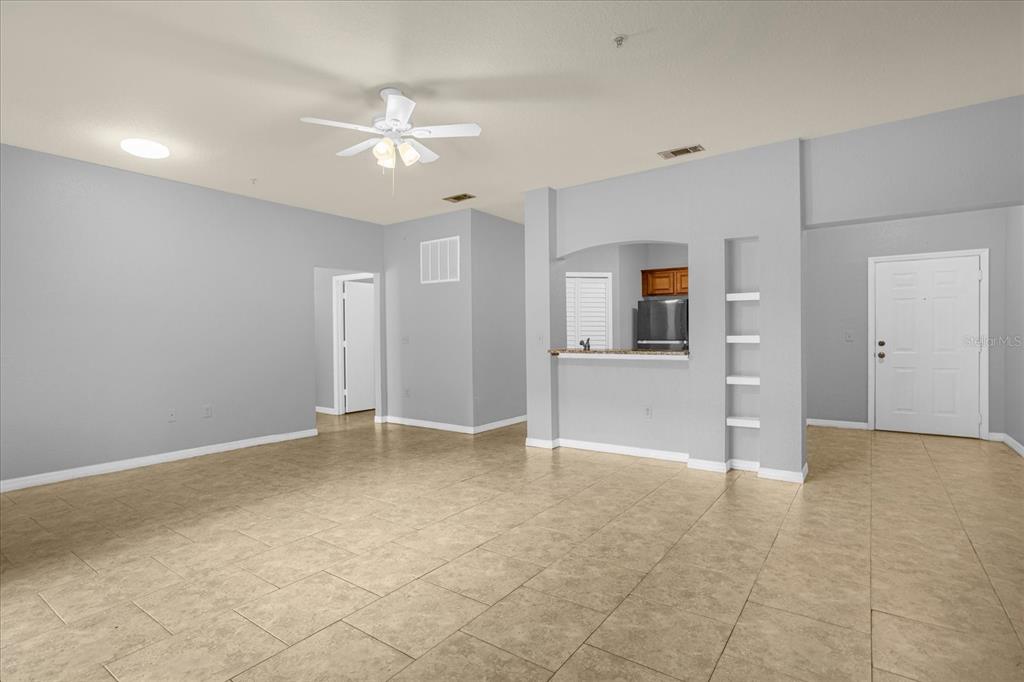 An open-concept living area features light gray walls, beige tile flooring, and a ceiling fan — 102 VISTA VERDI CIRCLE UNIT 100, LAKE MARY, FL