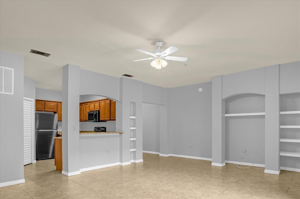 An open-concept living area with tile flooring, a ceiling fan, and an adjacent kitchen — 102 VISTA VERDI CIRCLE UNIT 100, LAKE MARY, FL