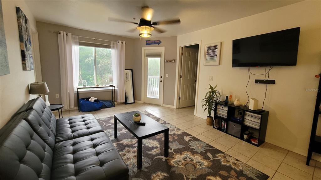 A living room features a black sofa, a coffee table, and a wall-mounted television — 4000 SW 23RD STREET UNIT 6-303, GAINESVILLE, FL