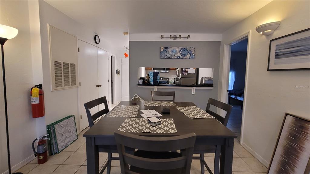 A dining area features a dark wooden table, chairs, and a pass-through to the kitchen — 4000 SW 23RD STREET UNIT 6-303, GAINESVILLE, FL