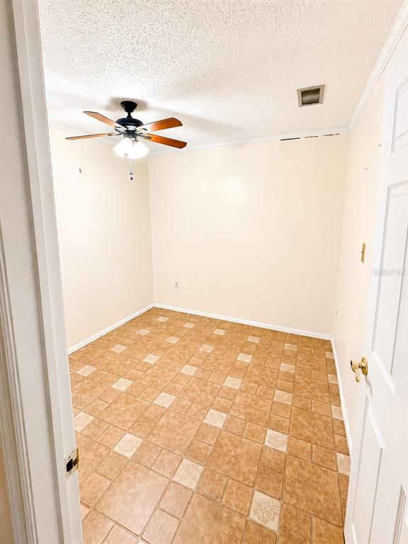 An empty room features beige walls, a ceiling fan, and brown patterned tile flooring — 3510 41ST AVENUE S UNIT 165, ST PETERSBURG, FL