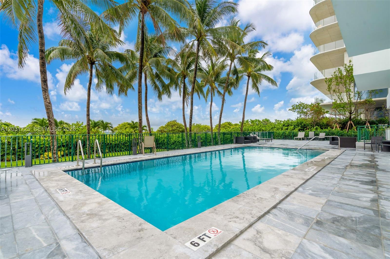 A rectangular swimming pool is surrounded by a stone deck and palm trees — 9195 Collins Ave # 601, Surfside FL 33154, SURFSIDE, FL