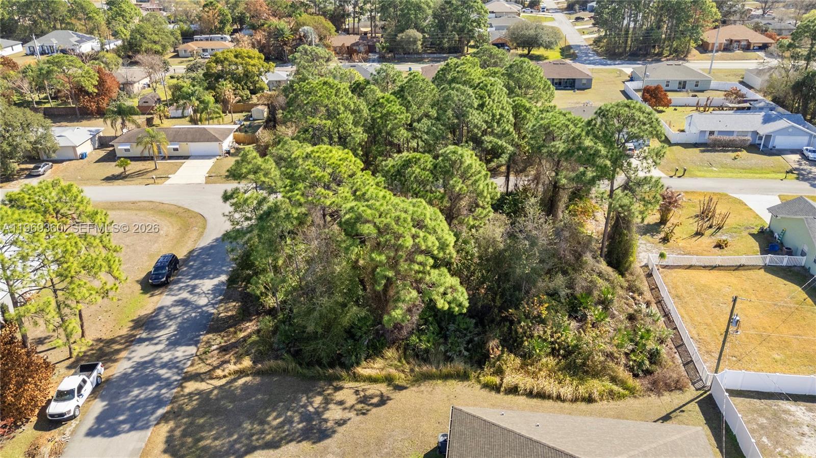 An aerial view shows a wooded vacant lot surrounded by residential houses and streets — 1070 Commerce RD SE, Palm Bay FL 32909, PALM BAY, FL