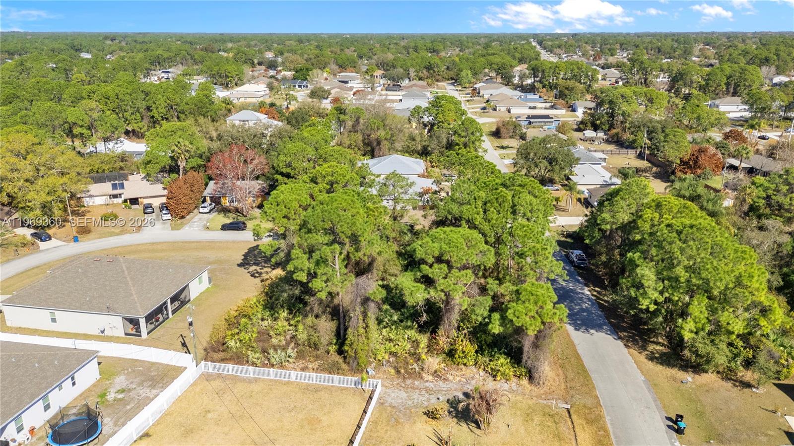 An aerial view shows a wooded residential lot situated between a paved road and houses — 1070 Commerce RD SE, Palm Bay FL 32909, PALM BAY, FL