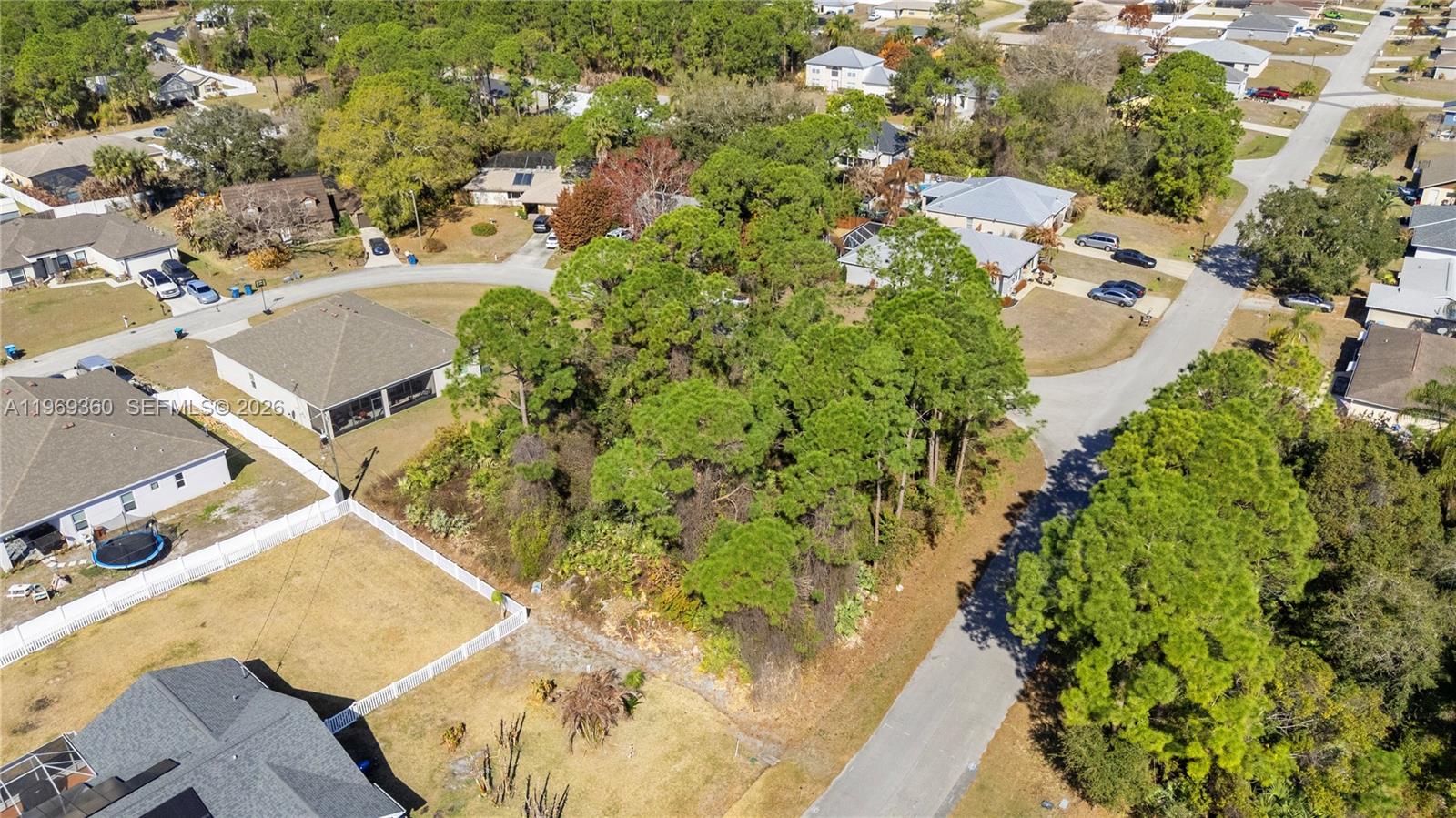 An aerial view shows a wooded vacant lot situated between residential houses and paved streets — 1070 Commerce RD SE, Palm Bay FL 32909, PALM BAY, FL
