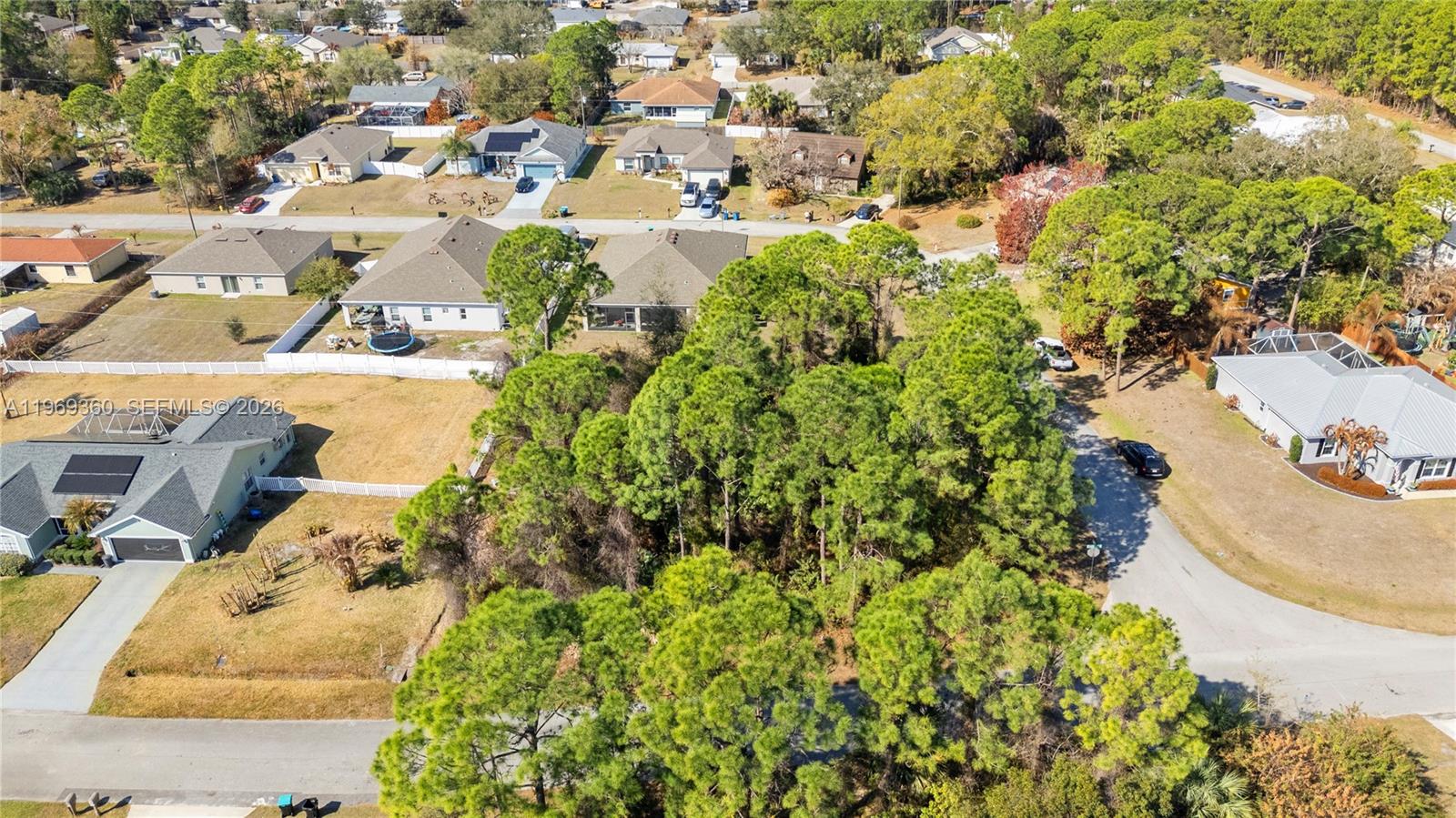 An aerial view shows a wooded lot surrounded by residential houses and paved streets — 1070 Commerce RD SE, Palm Bay FL 32909, PALM BAY, FL