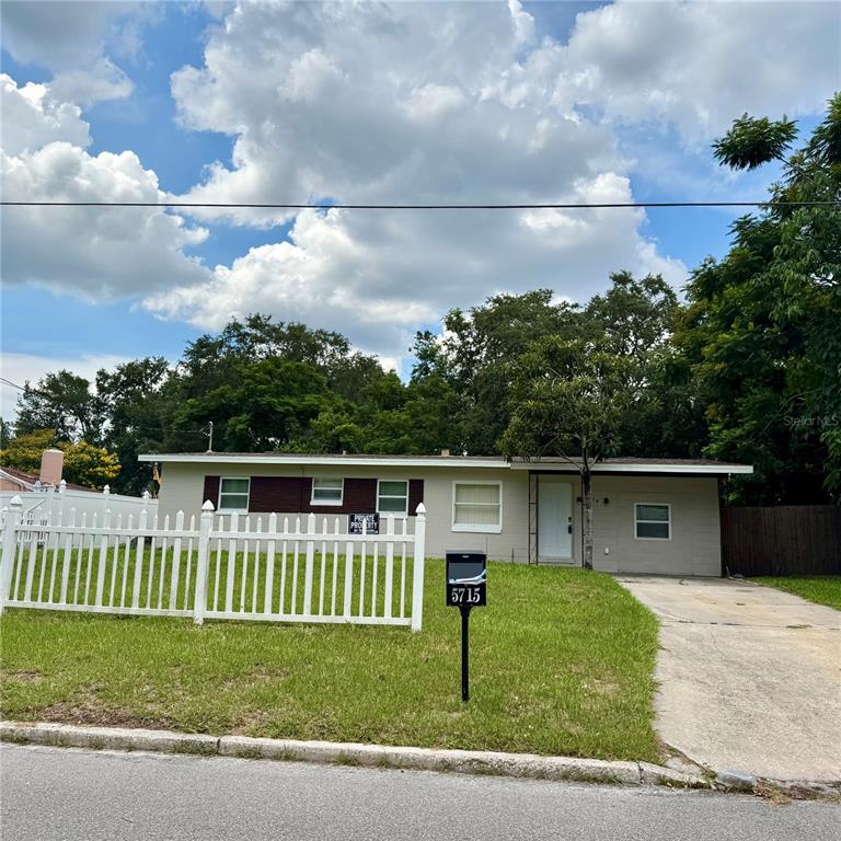 A single-story house with a white picket fence, a concrete driveway, and a grassy lawn — 5715 ELON DRIVE, ORLANDO, FL