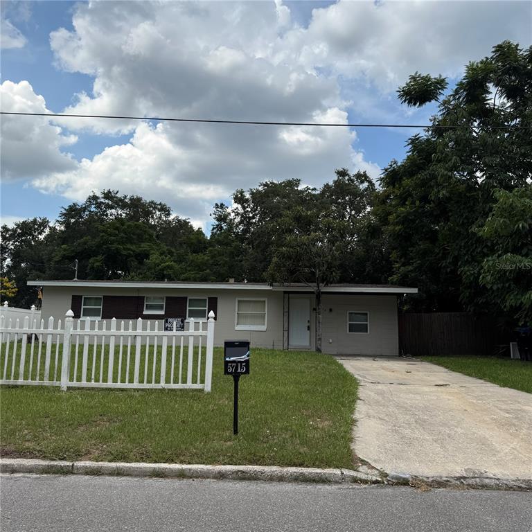 A single-story house with a white picket fence, a concrete driveway, and a mailbox — 5715 ELON DRIVE, ORLANDO, FL