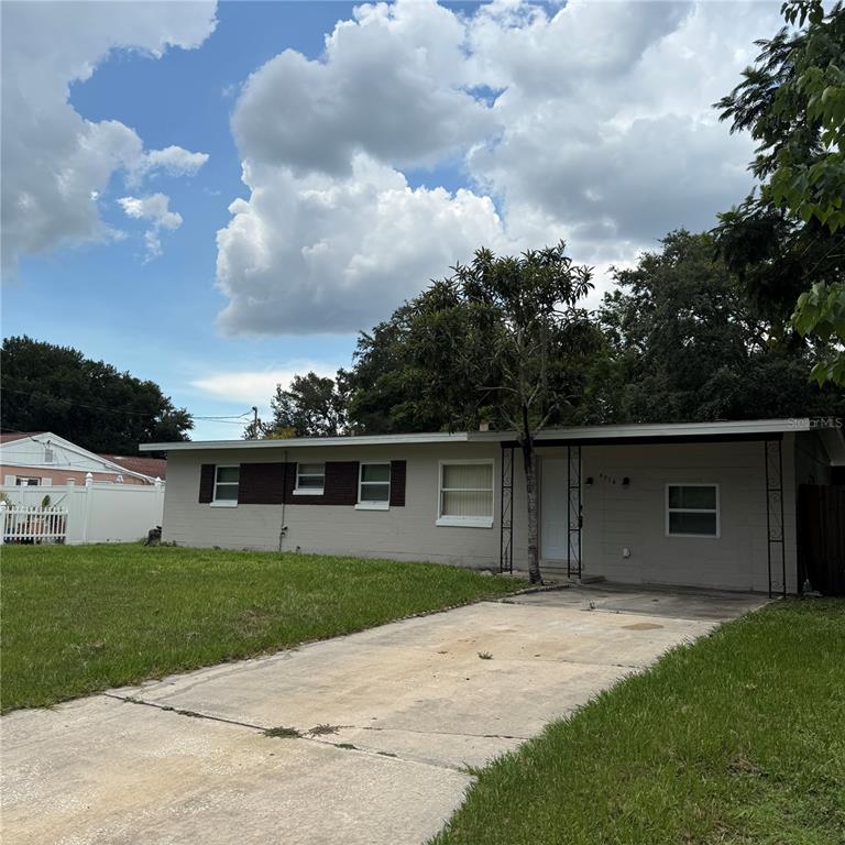 A single-story house with a beige exterior, a concrete driveway, and a covered front porch — 5715 ELON DRIVE, ORLANDO, FL