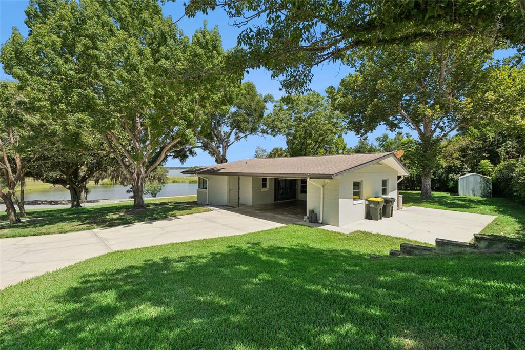A single-story house with a carport and driveway sits on a grassy lot near water — 290 CARROLL STREET, CLERMONT, FL