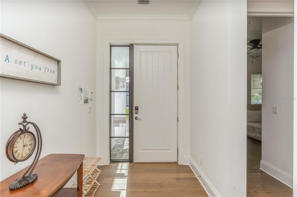 A bright entryway features a white front door with a side window and wood flooring — 132 OCEAN ESTATES DRIVE, HUTCHINSON ISLAND, FL