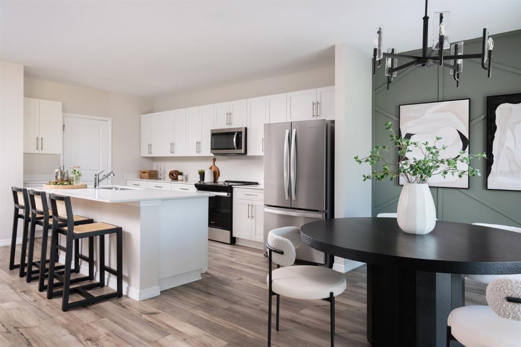 A modern kitchen and dining area with white cabinetry, stainless appliances, and a round table — 1707 VANILLA STREET, HAINES CITY, FL