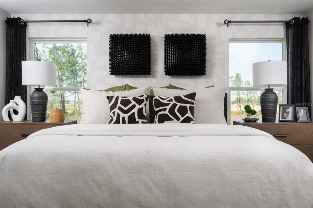A bedroom features a bed with patterned pillows, two black wall art pieces, and bedside lamps — 1707 VANILLA STREET, HAINES CITY, FL