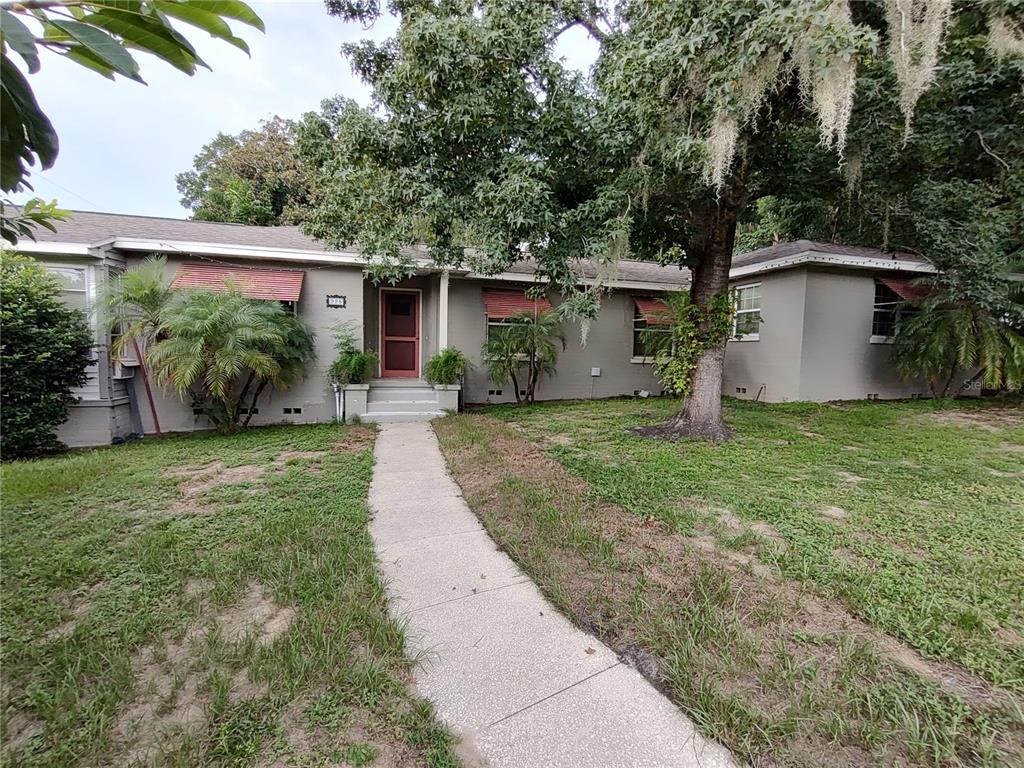 A single-story house with a gray exterior, a concrete walkway, and large trees in front — 995 W 11TH AVENUE, MOUNT DORA, FL