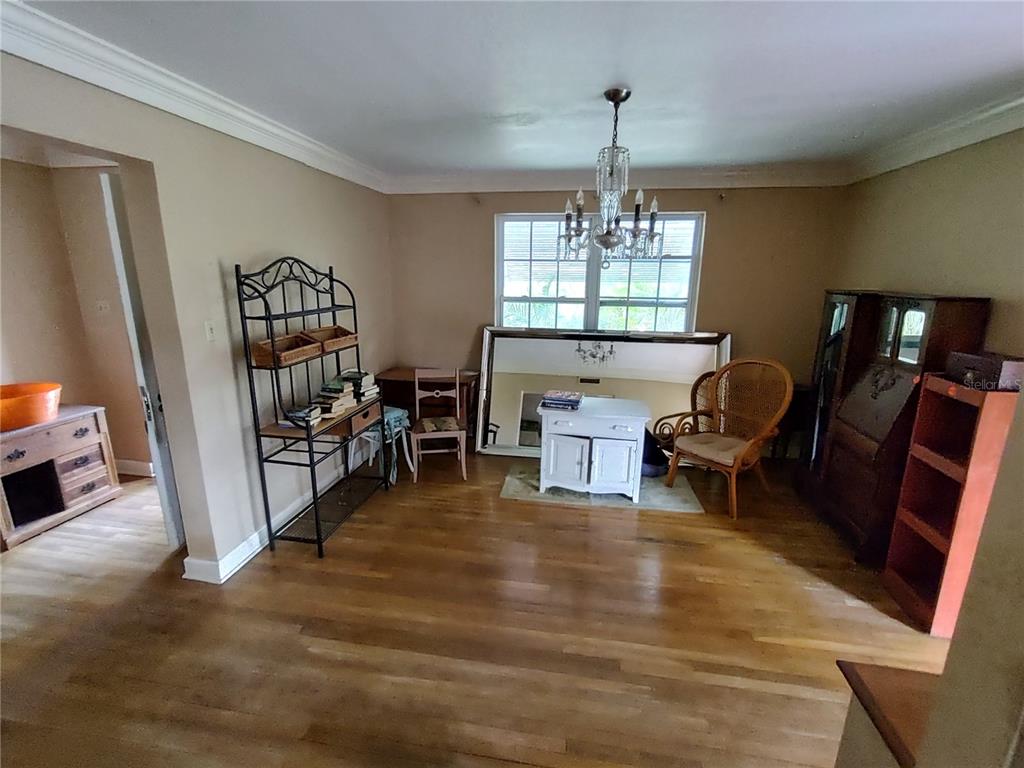 A dining room with hardwood floors, a crystal chandelier, and various pieces of wooden furniture — 995 W 11TH AVENUE, MOUNT DORA, FL