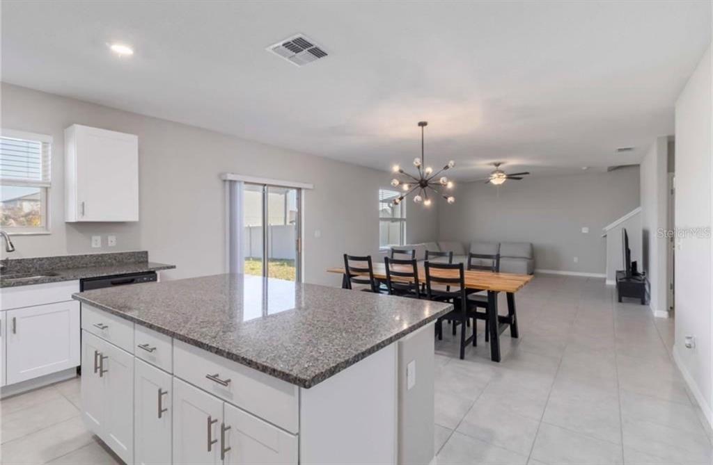 A kitchen island with granite countertops overlooks a dining area and living space — 5478 GRAYS HARBOR COURT, WIMAUMA, FL