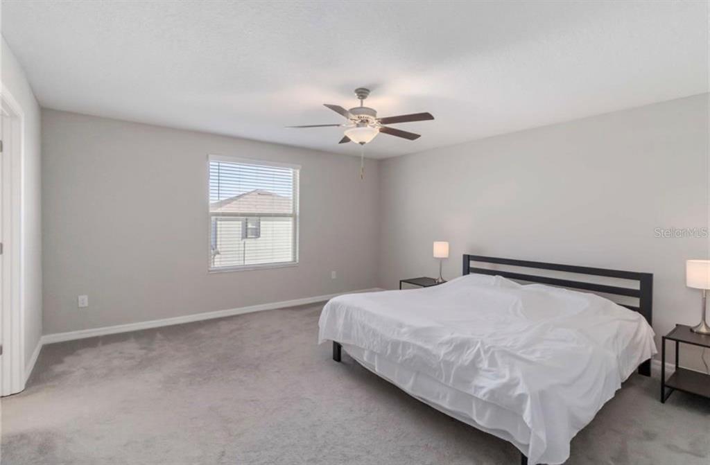 A bedroom with gray carpet, light walls, a ceiling fan, and a bed with white bedding — 5478 GRAYS HARBOR COURT, WIMAUMA, FL